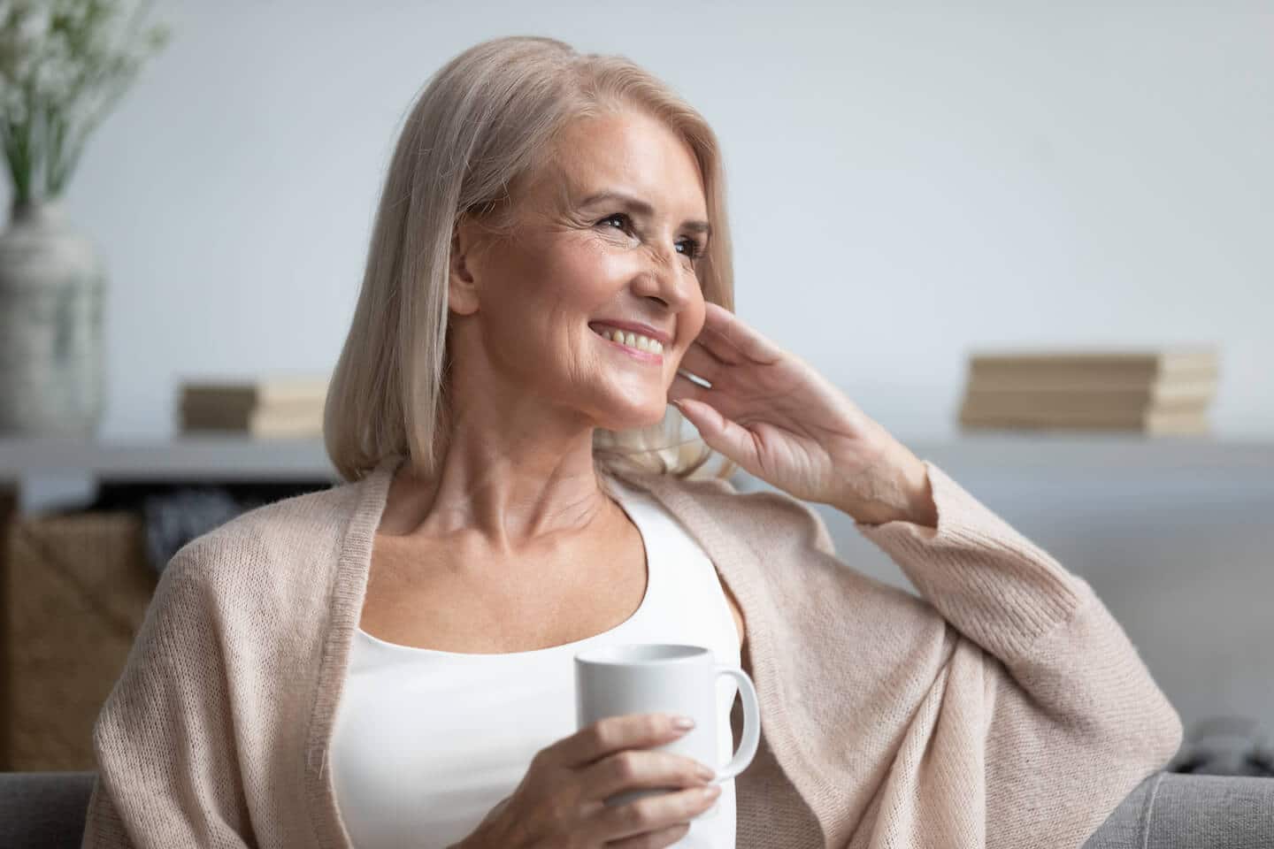 a senior woman smiling while drinking a cup of coffee
